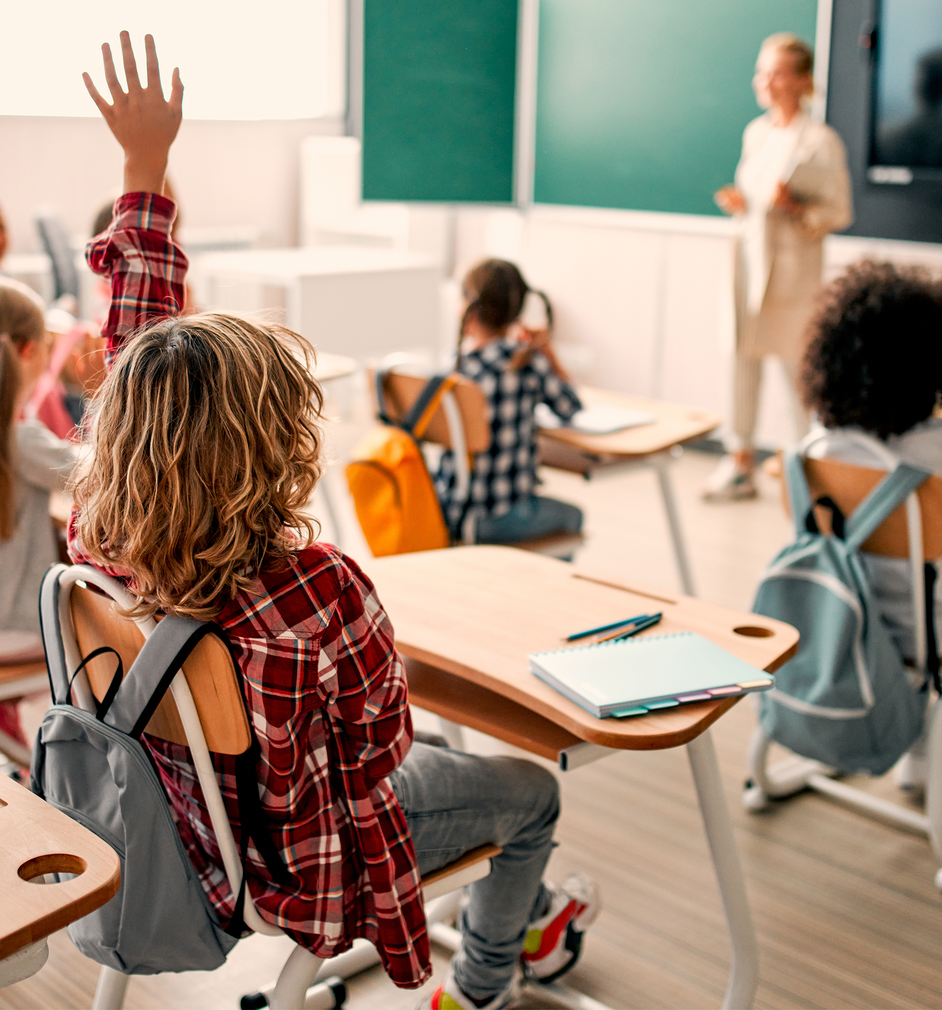 child raising hand in classroom